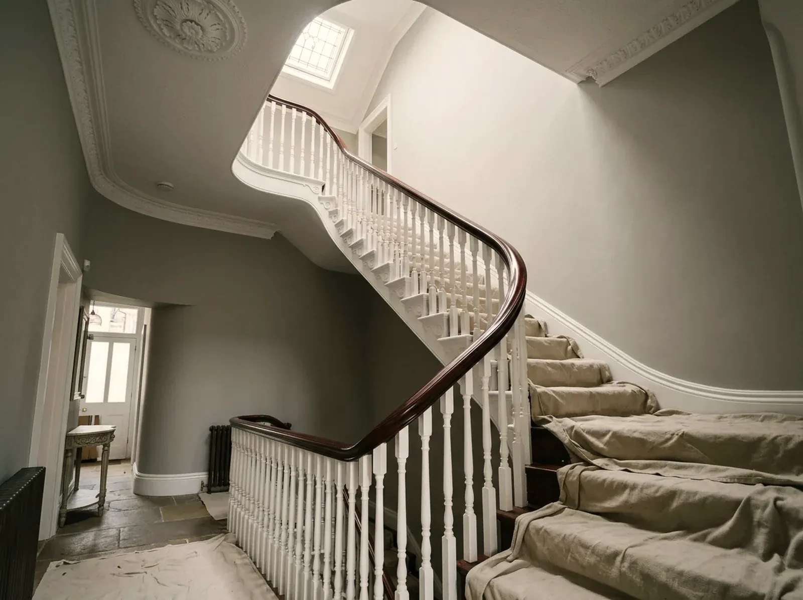 Three-storey period hallway with dust sheets laid over the stair treads and the balustrade masked ready for decorating